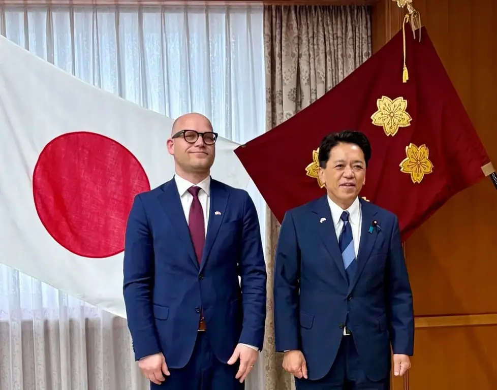 Statssekreterare Andreas Flåm och japansk viceminister skakar hand framför norska och japanska flaggor.
